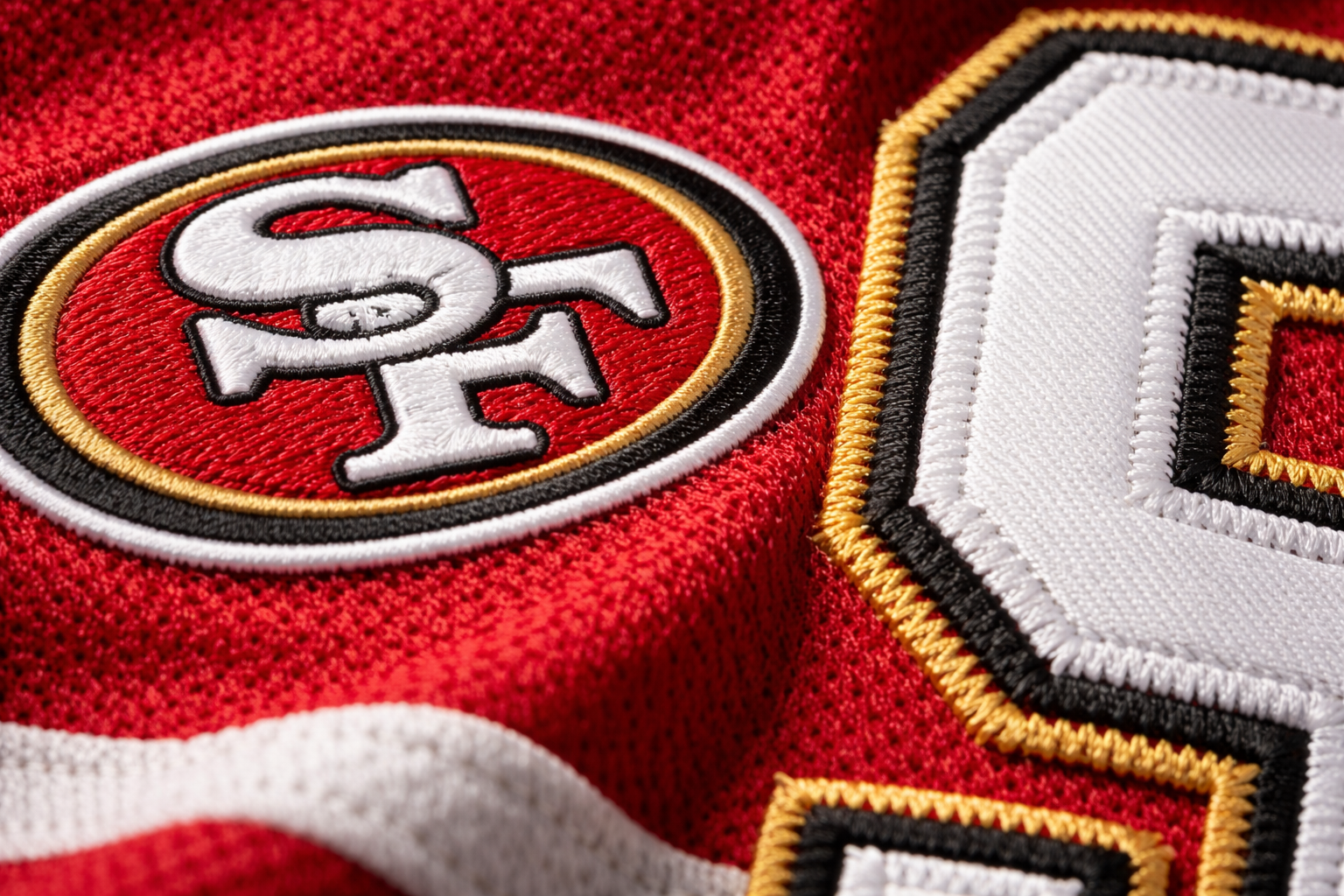 Macro close up of the 'SF' logo and stitched numbers on a 49ers jersey
