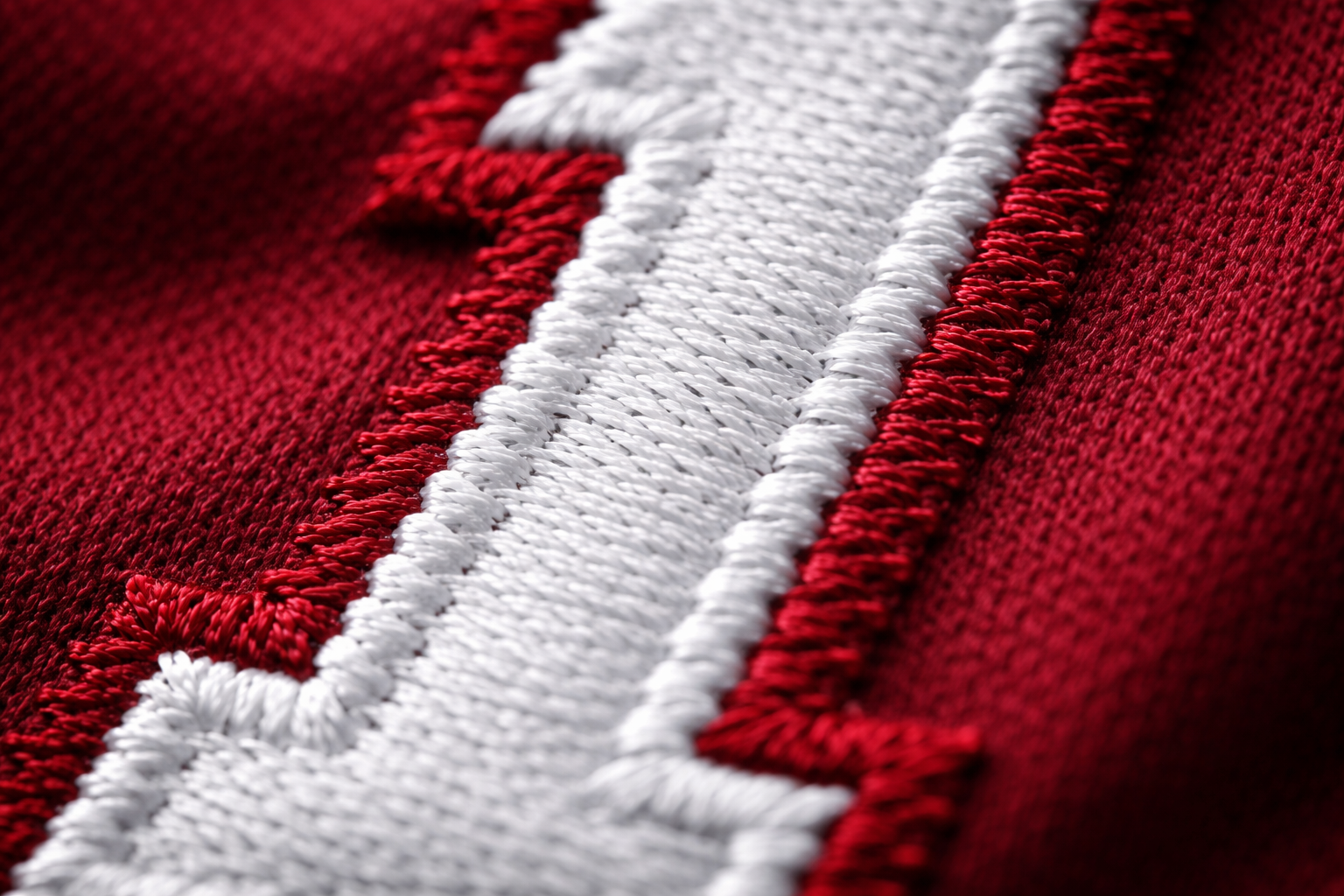 Macro close up of stitched white numbers on a crimson Alabama jersey.