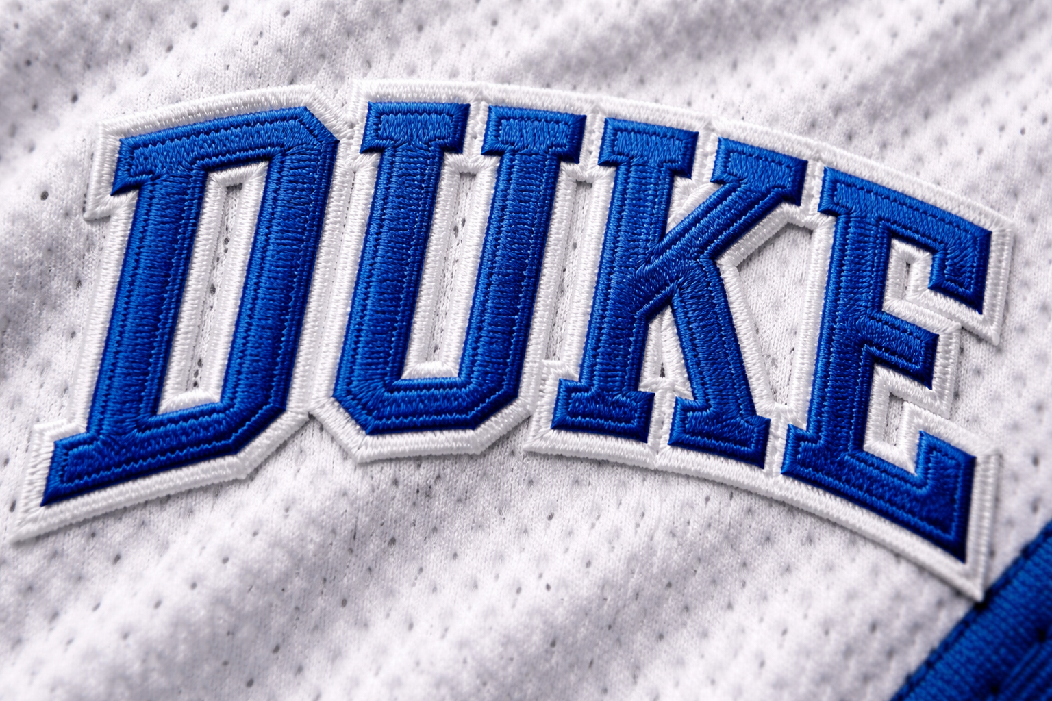 Macro close up of the stitched 'DUKE' script on a white basketball jersey