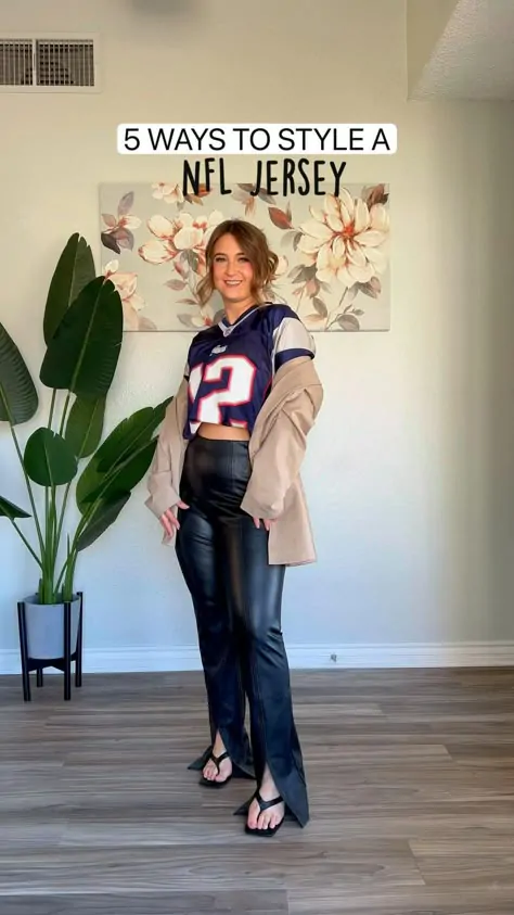 Fan wearing a football jersey over a grey hoodie for cold weather style.