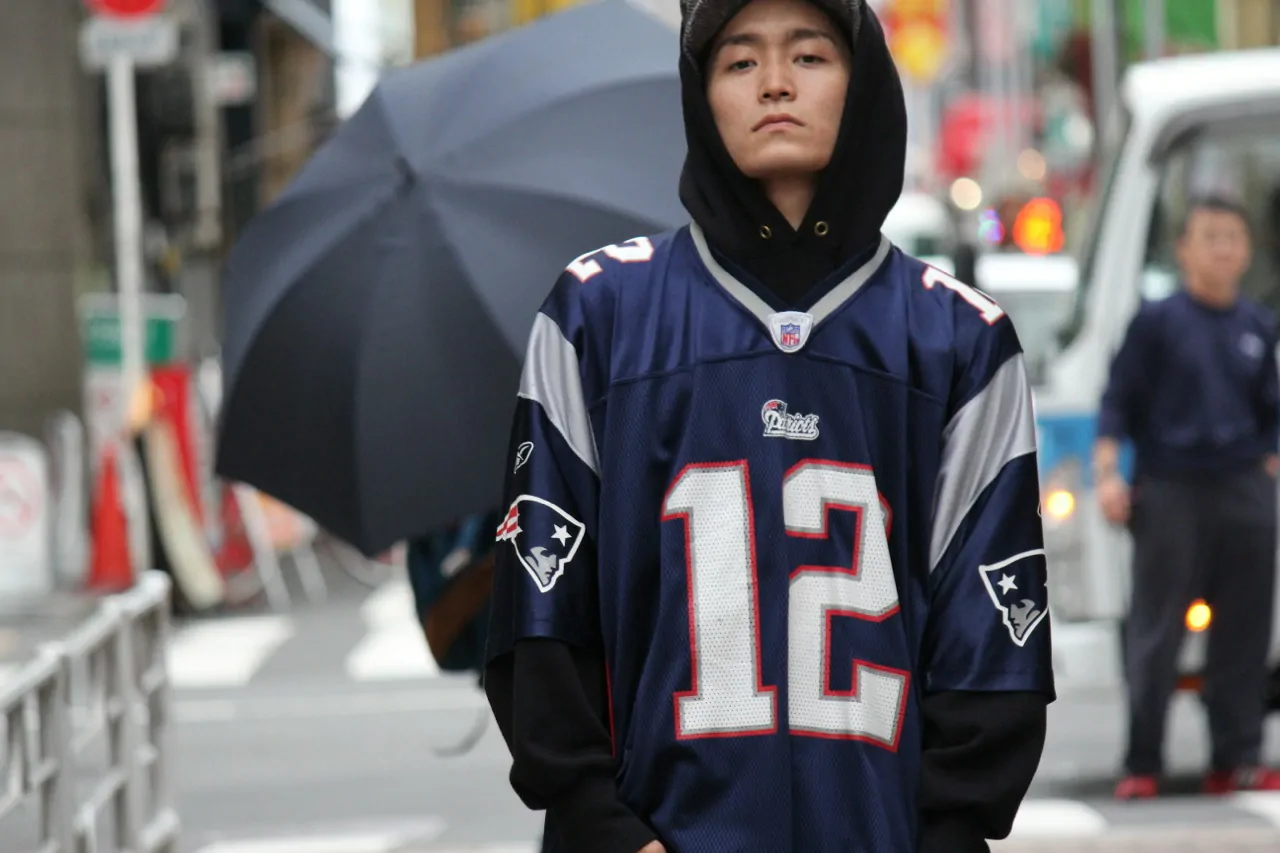 Fan wearing a hoodie under a stitched NFL jersey for a layered look