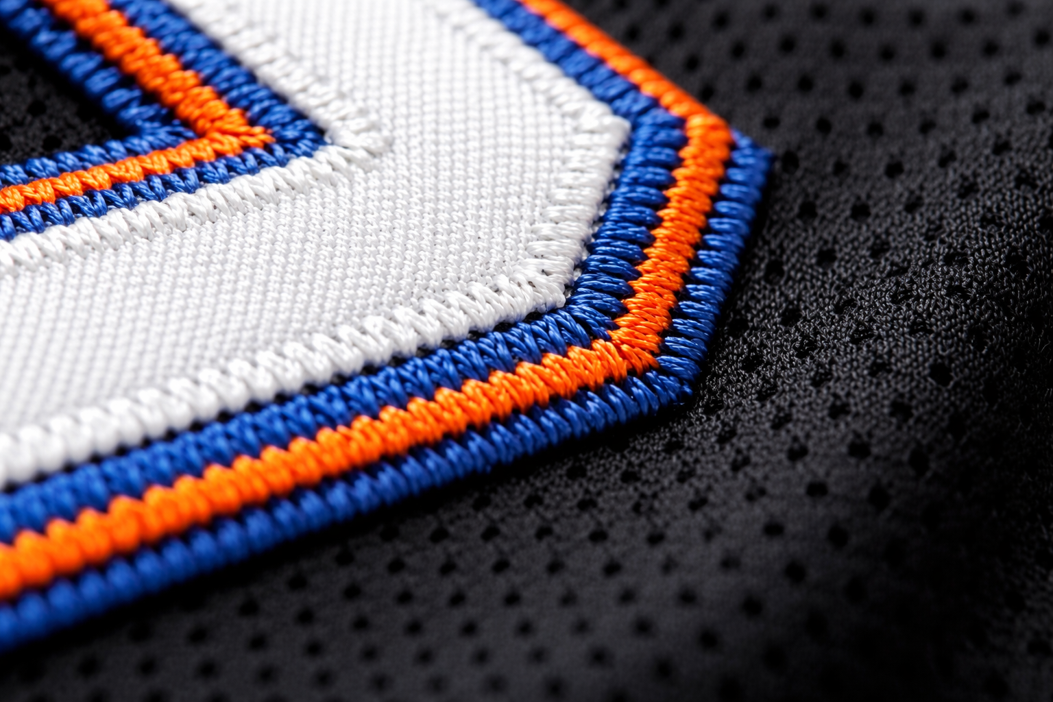 Macro close up of the blue and orange stitched drop shadow numbers on a Mets jersey.