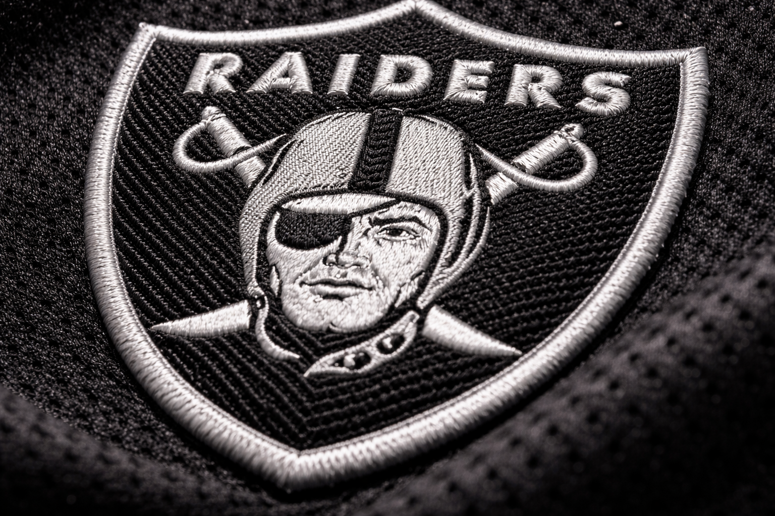 Macro close up of the stitched silver pirate logo on a Raiders jersey.