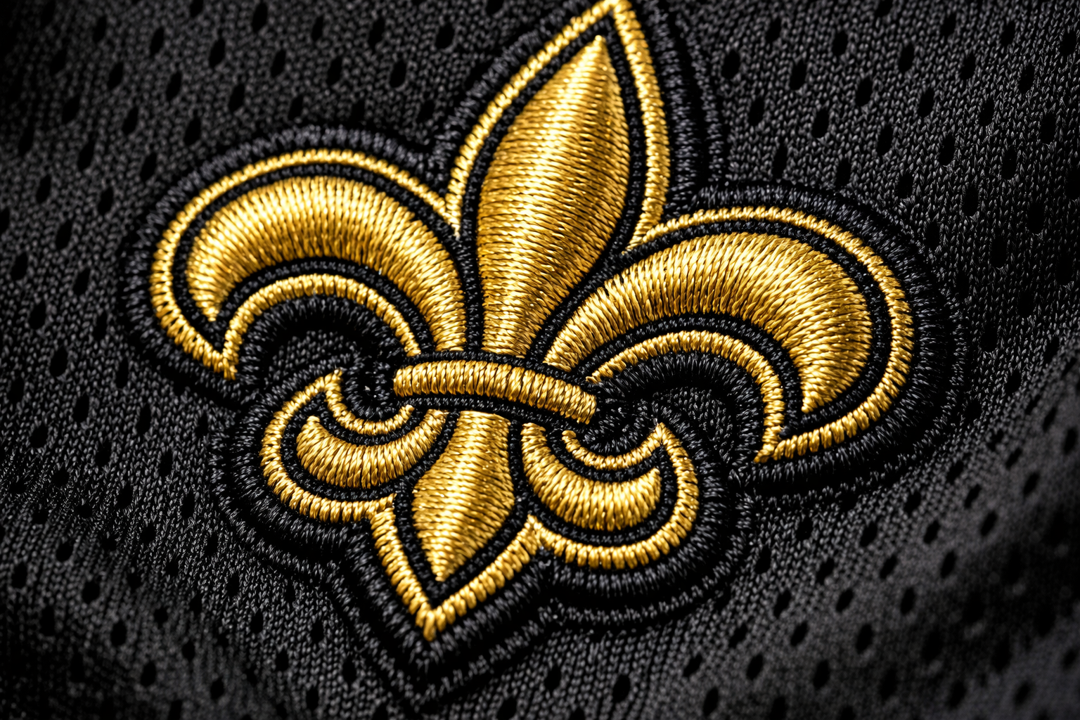 Macro close up of the gold stitched Fleur-de-lis logo on a Saints jersey.