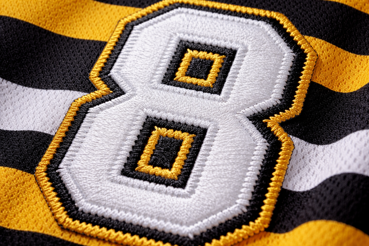 Macro close up of the white stitched number on a yellow and black striped jersey.