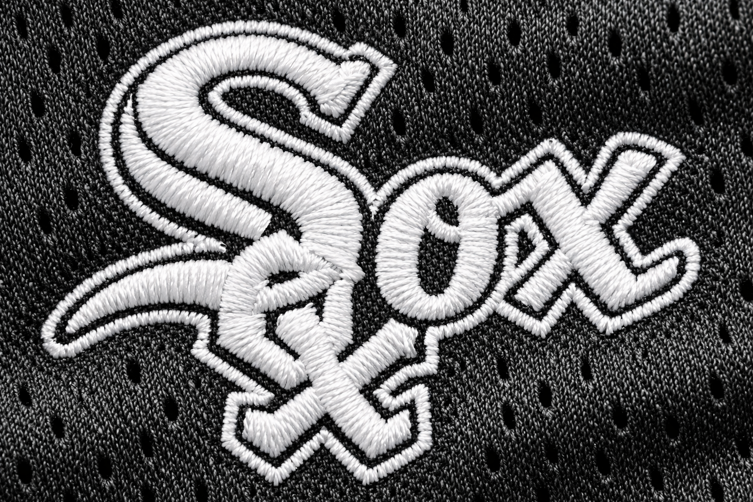 Macro close up of the white stitched Sox script on a black jersey.
