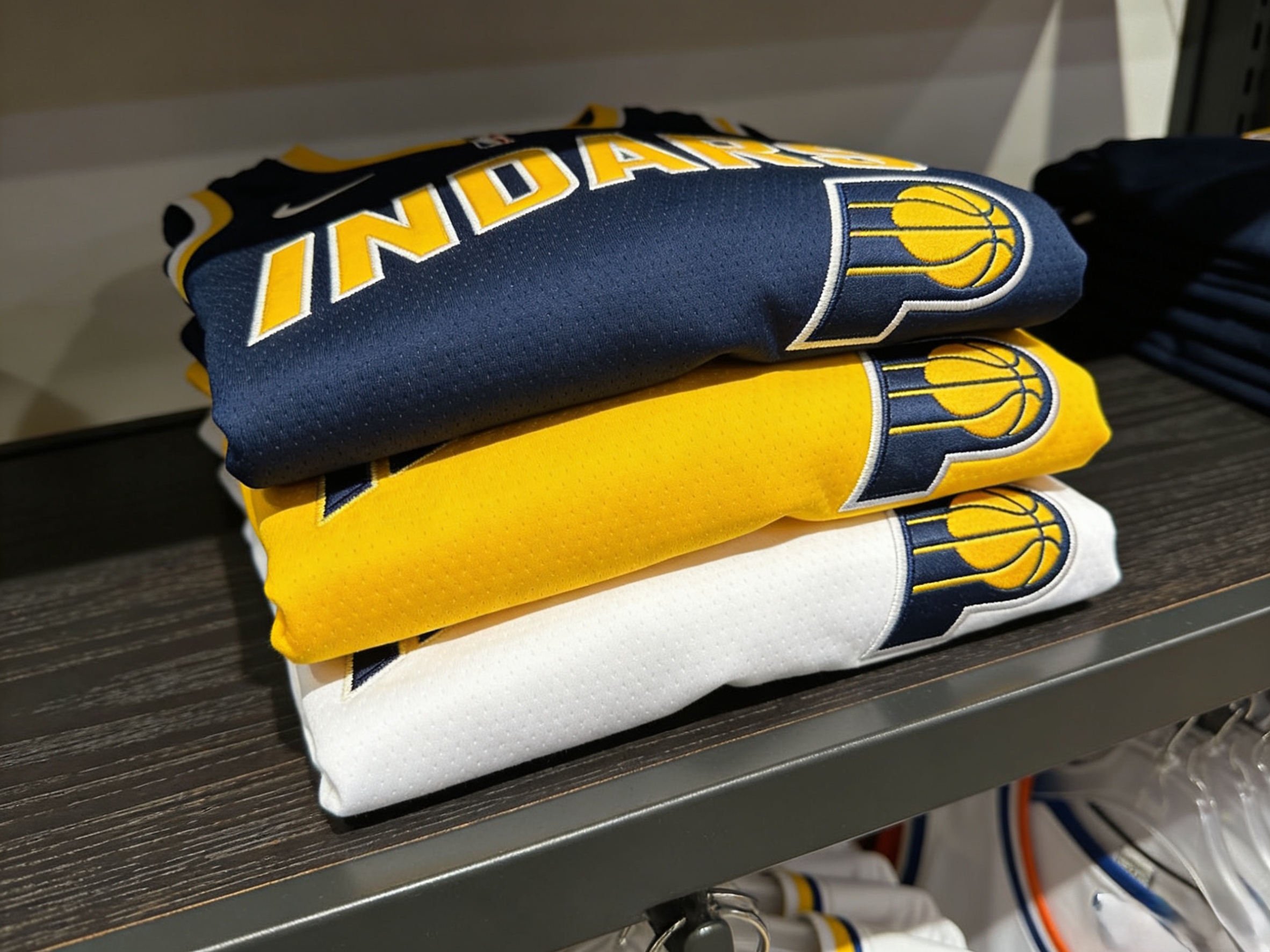 A stack of folded Indiana Pacers jerseys in various colors