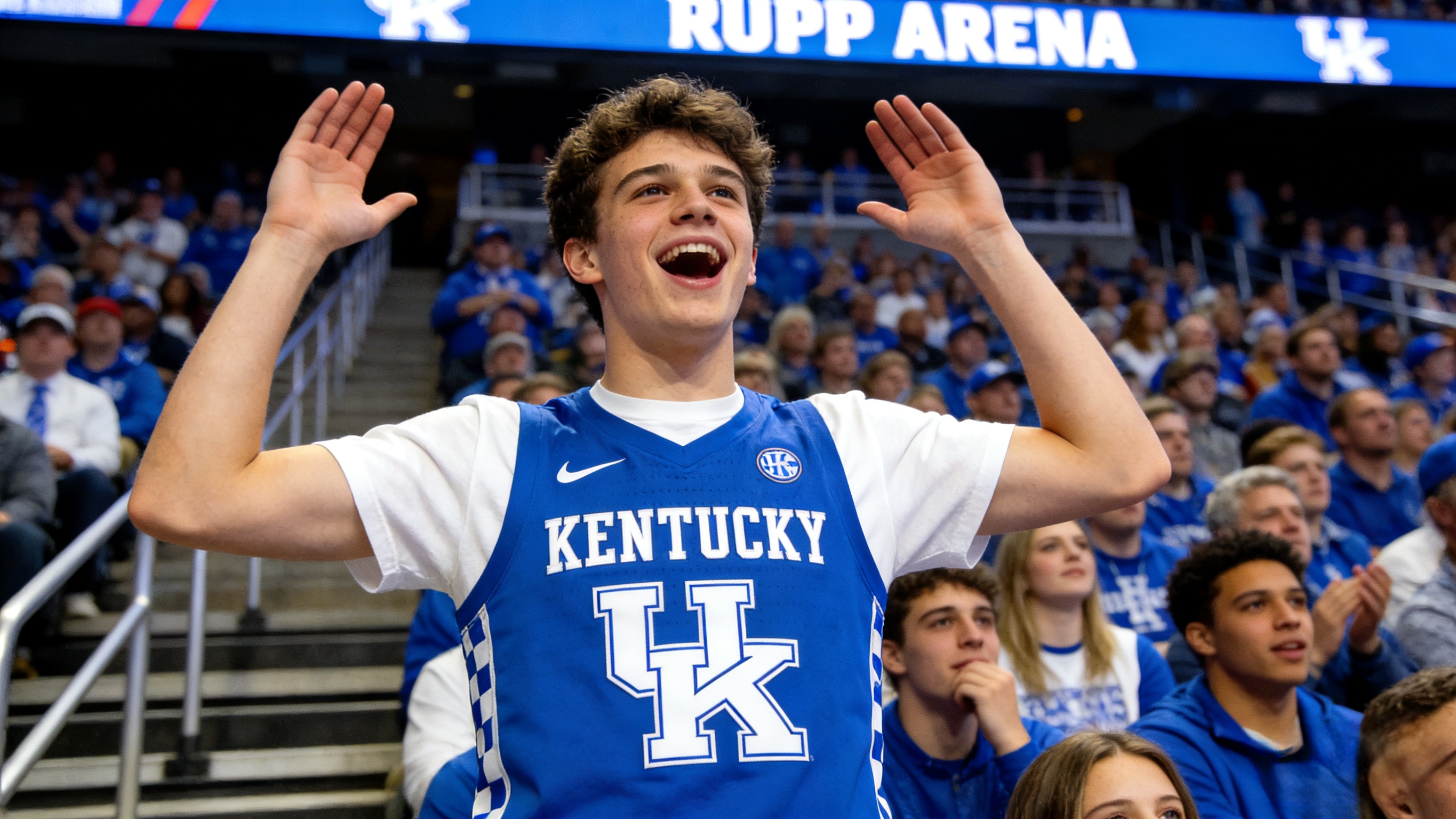 A fan wearing a Kentucky Wildcats jersey cheering at a college basketball arena.