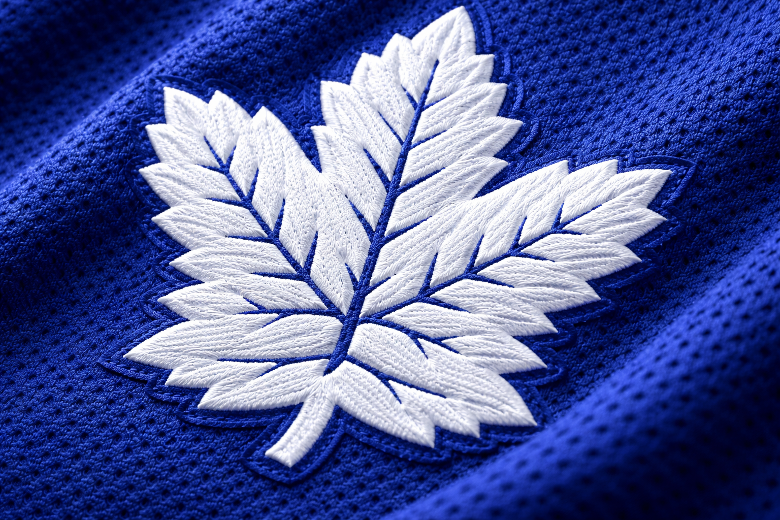 Toronto Maple Leafs Jersey: Authentic vs. Breakaway Guide 3 Macro close up of the white stitched Maple Leaf logo on a blue jersey.