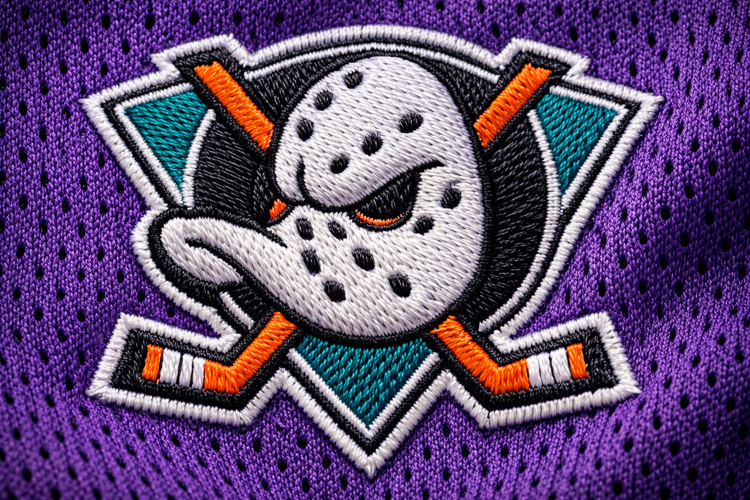 Macro close up of the stitched duck mask logo on a hockey jersey.