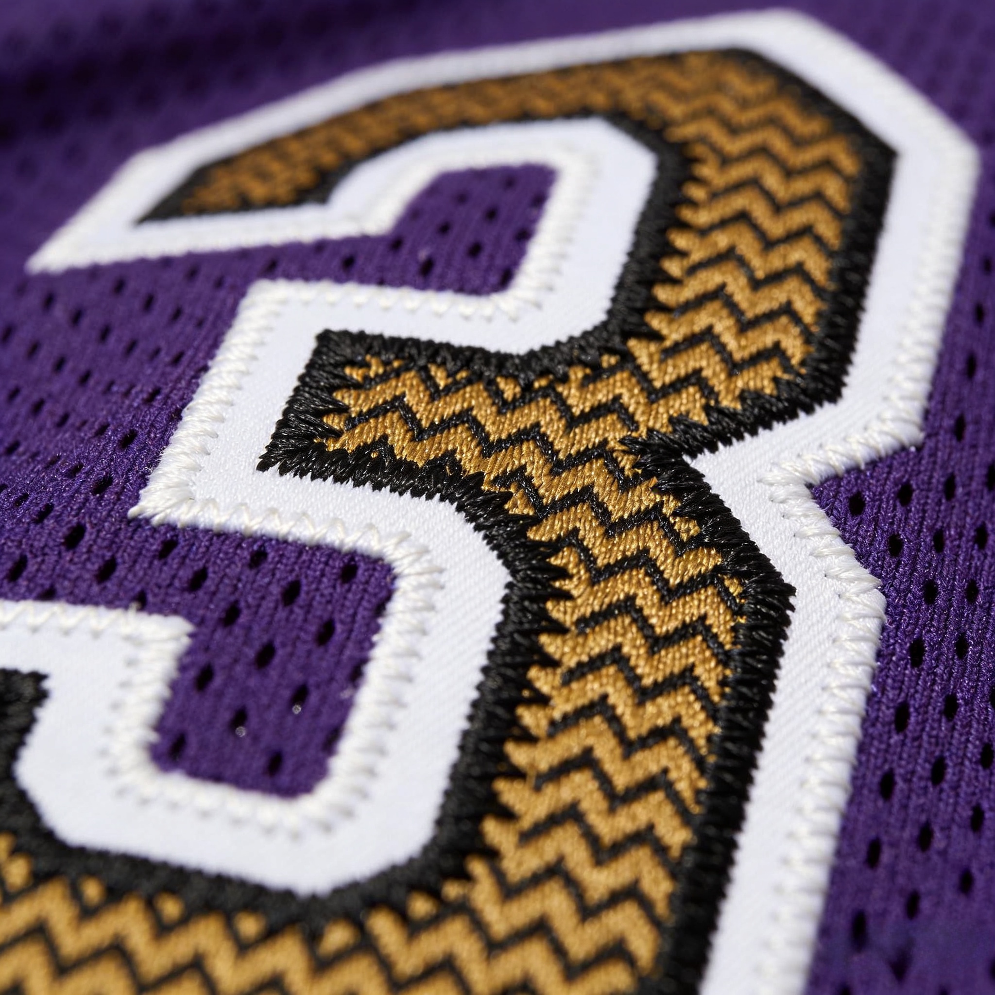 Macro close up of the white and gold stitched numbers on a purple Ravens jersey