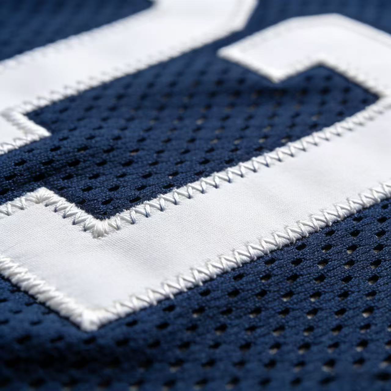 Macro close up of the high-quality stitching on a Ujersery football jersey.