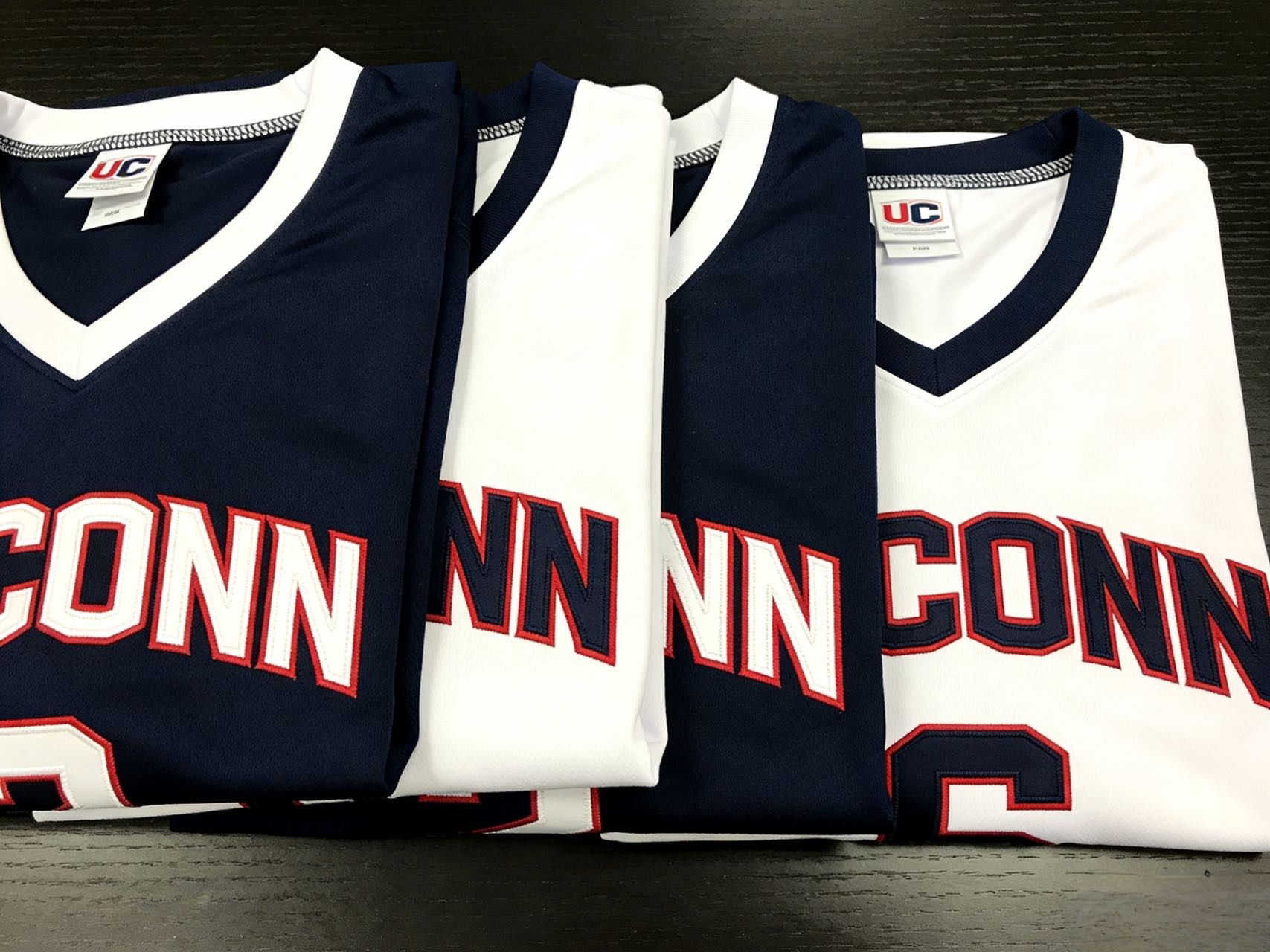 Neatly folded UConn basketball jerseys in navy and white colors