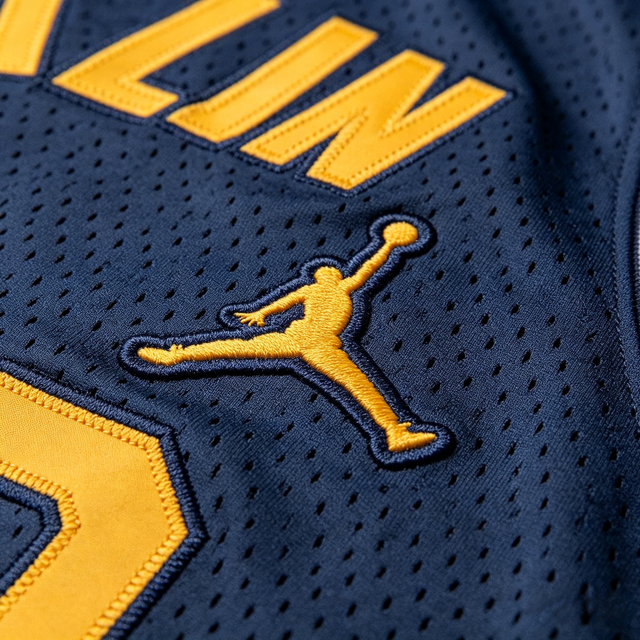 Close-up of stitched Jumpman logo and maize numbers on a Michigan jersey