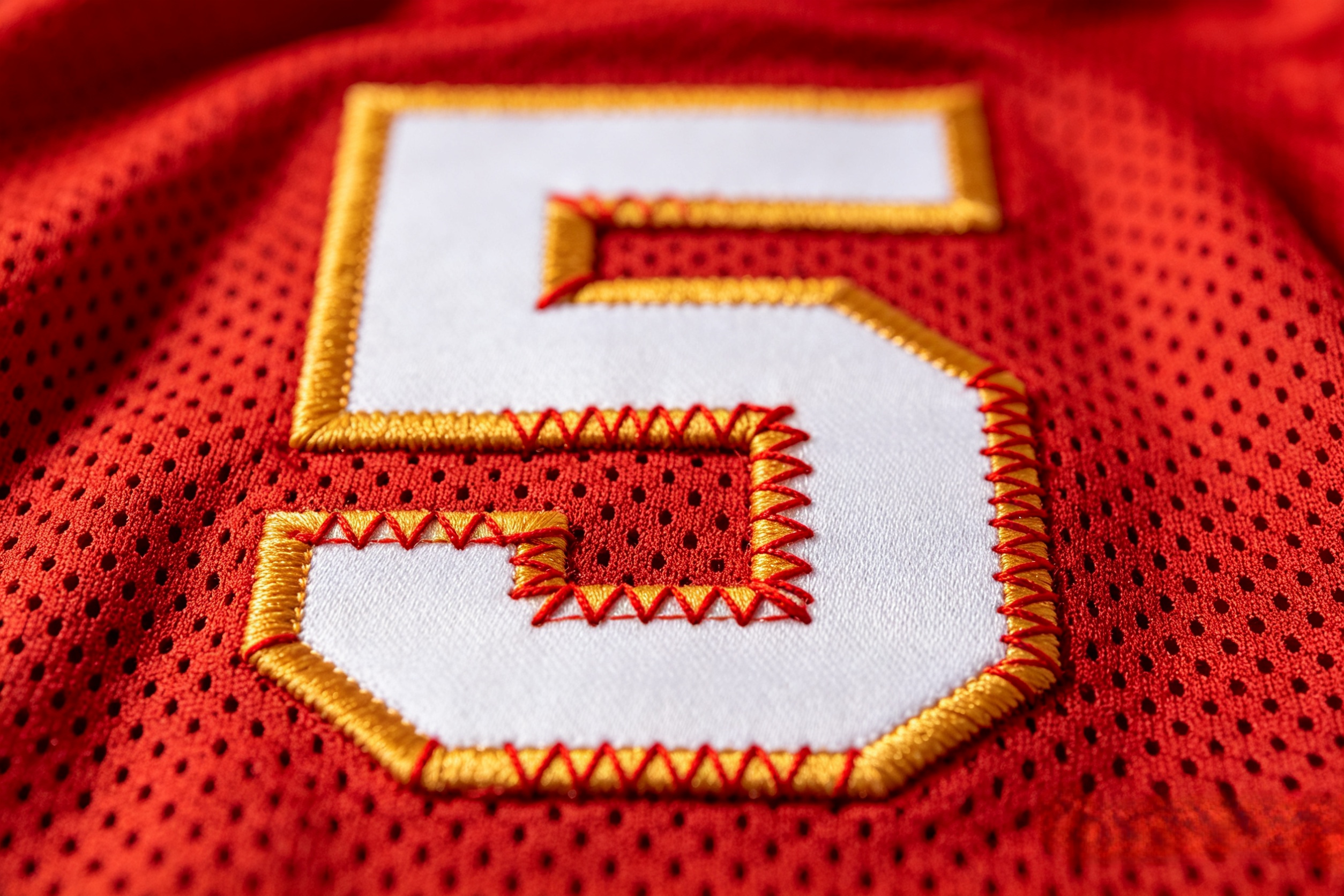 Detailed close-up of premium gold embroidery on a Chiefs jersey